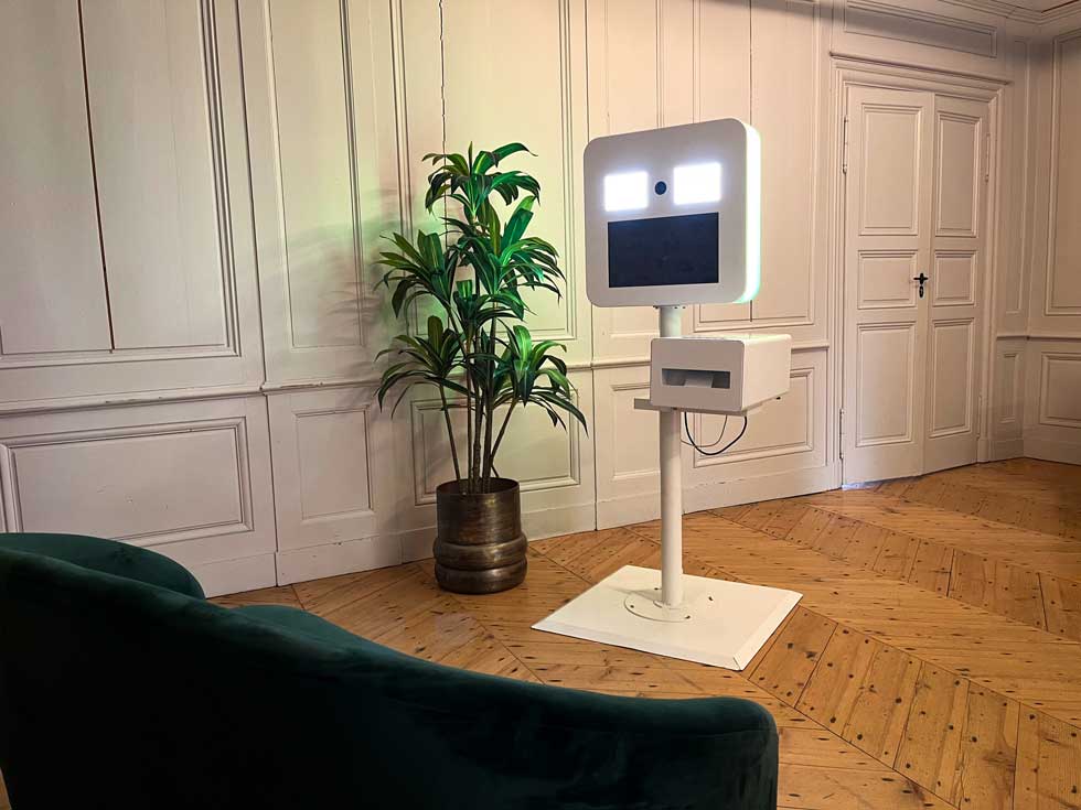 Borne blanche à selfie au milieu d'un salon avec du parquet en bois